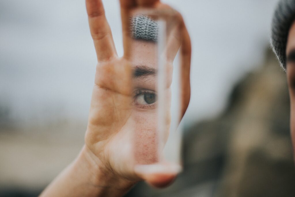 Photo d'une main qui tient un tube transparent. On aperçoit le reflet de la personne à travers le tube. Elle semble en accord avec l'image qu'elle renvoie d'elle-même. La photo illustre la puissance d'une page à propos personnalisée et sur mesure.